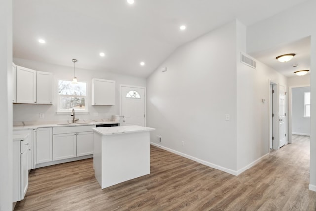 kitchen featuring light wood-style flooring, a sink, visible vents, a center island, and plenty of natural light