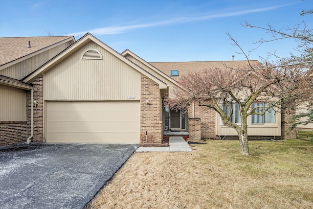 view of front of home featuring brick siding, aphalt driveway, roof with shingles, an attached garage, and a front yard