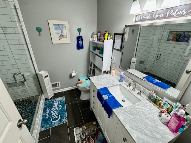 bathroom featuring tile patterned floors, vanity, toilet, and a shower with shower door