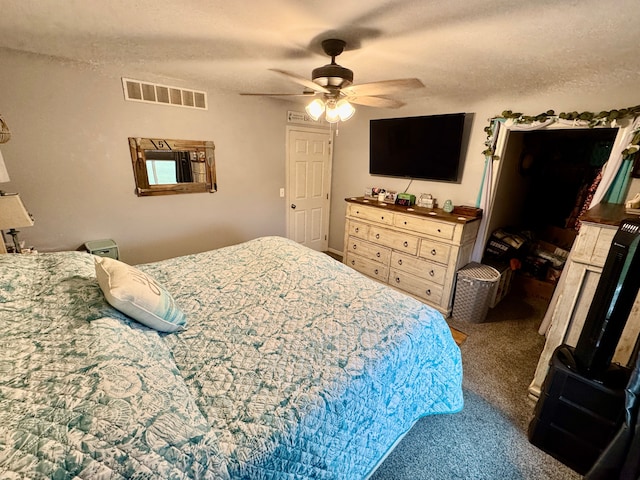 carpeted bedroom featuring ceiling fan and a textured ceiling