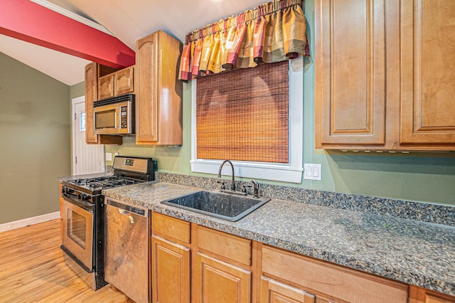 kitchen featuring stainless steel appliances, vaulted ceiling, sink, and light hardwood / wood-style flooring