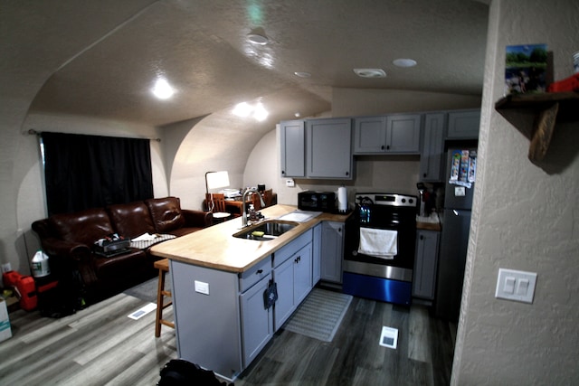 kitchen with electric range, sink, kitchen peninsula, wood-type flooring, and lofted ceiling