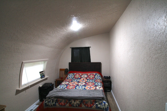 bedroom with a textured ceiling and vaulted ceiling