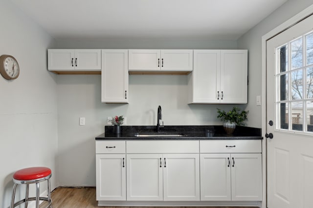 kitchen with white cabinetry, sink, and light hardwood / wood-style flooring