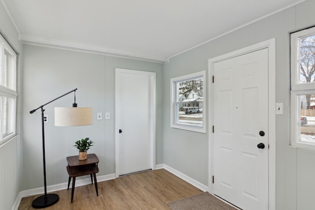 foyer featuring crown molding, a wealth of natural light, and light hardwood / wood-style flooring