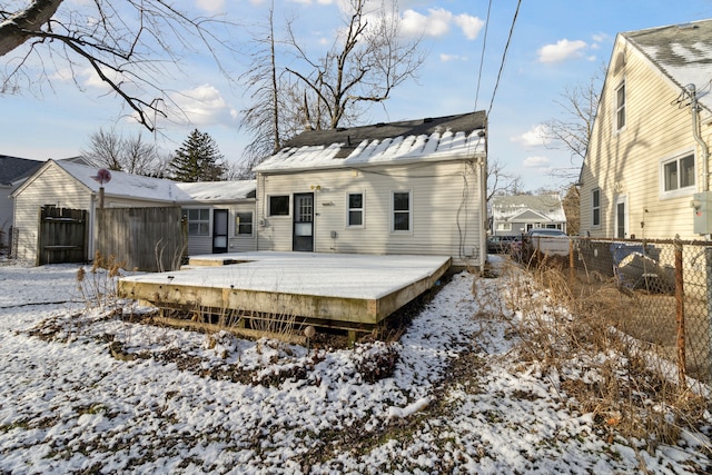 snow covered back of property featuring a deck