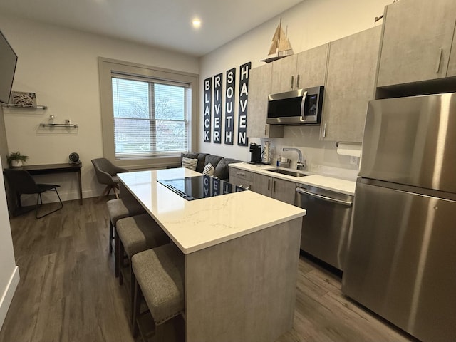 kitchen featuring appliances with stainless steel finishes, sink, dark hardwood / wood-style floors, a kitchen island, and a breakfast bar area