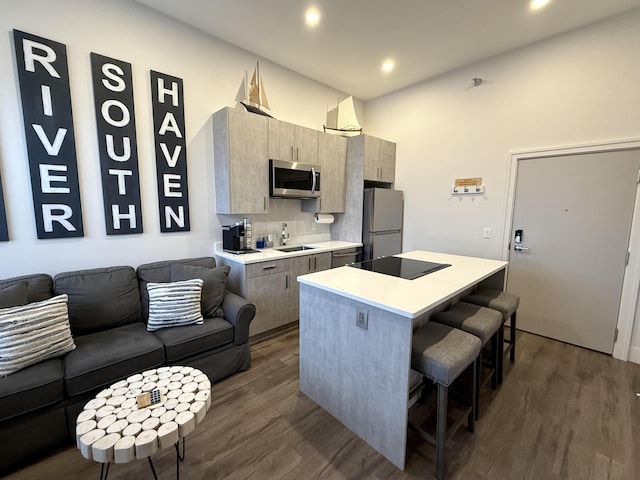 kitchen featuring sink, stainless steel appliances, dark hardwood / wood-style flooring, a breakfast bar, and a kitchen island