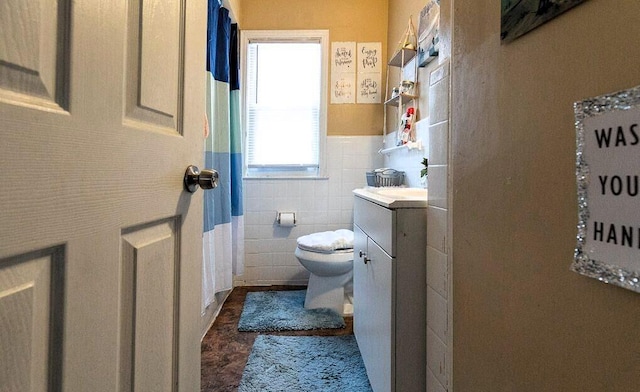 bathroom with vanity, toilet, and tile walls