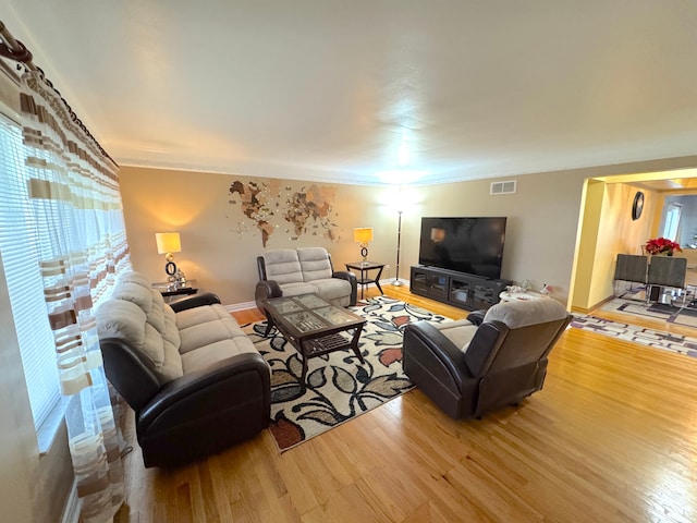 living room featuring a healthy amount of sunlight, wood-type flooring, and ornamental molding