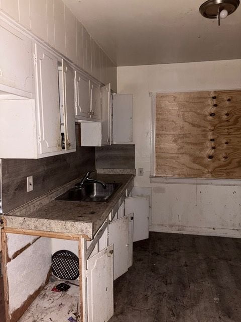 kitchen with tasteful backsplash, white cabinetry, and sink