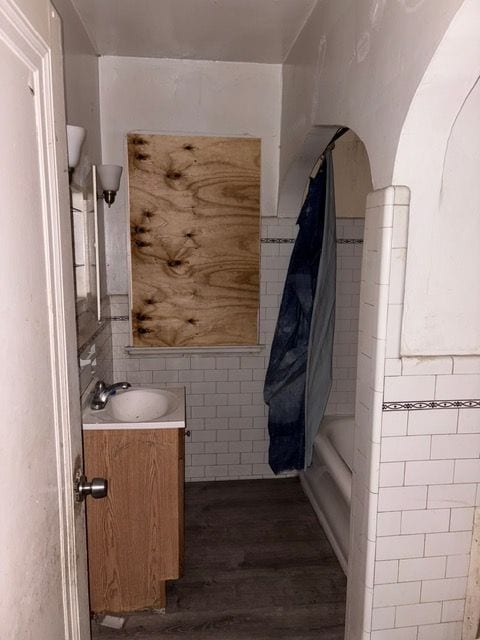 bathroom featuring shower / tub combo, vanity, wood-type flooring, and tile walls