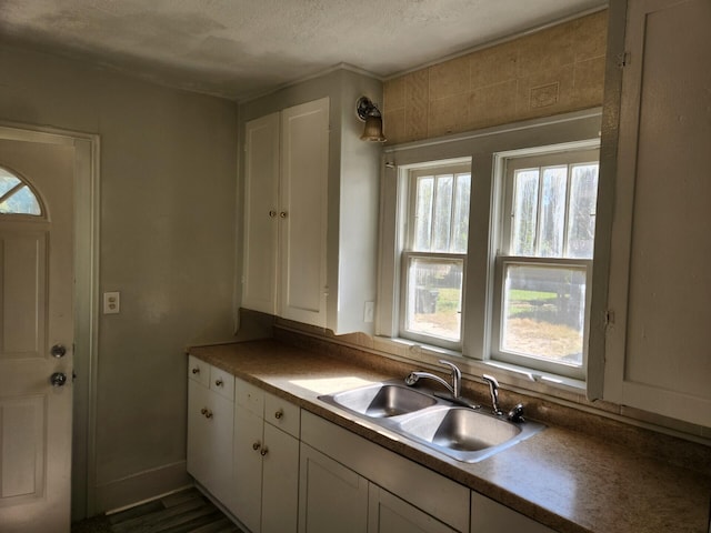 kitchen with white cabinetry, sink, and a textured ceiling