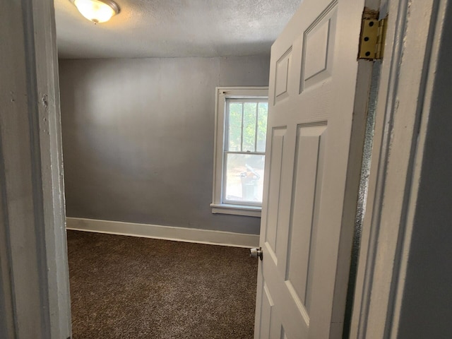 empty room with a textured ceiling and dark carpet