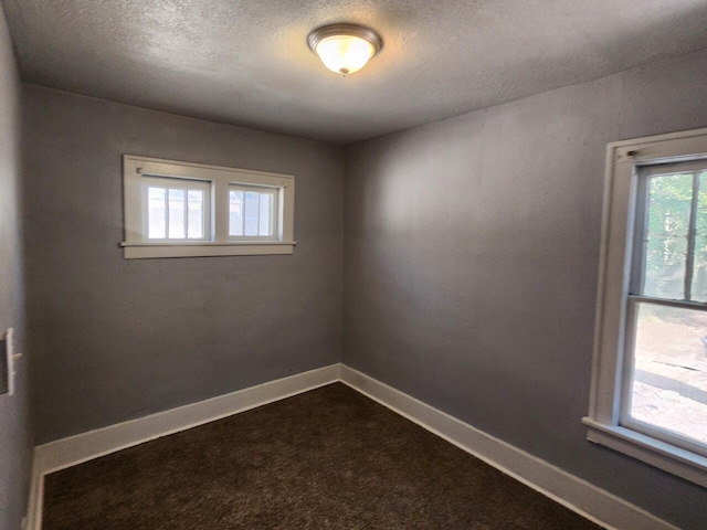 spare room with dark colored carpet and a textured ceiling