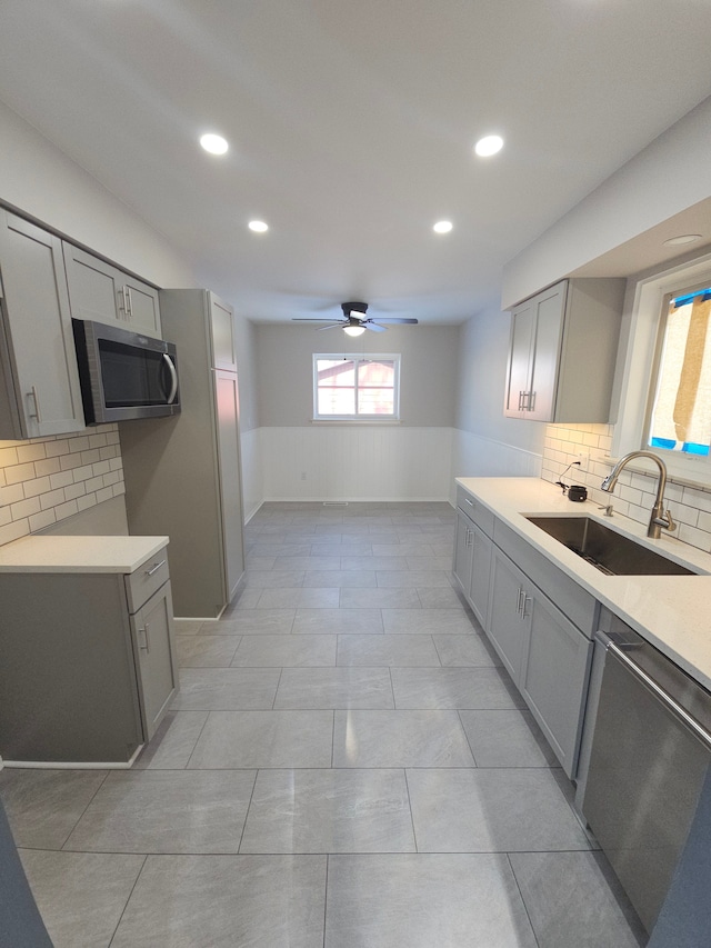 kitchen featuring backsplash, stainless steel appliances, ceiling fan, sink, and gray cabinets