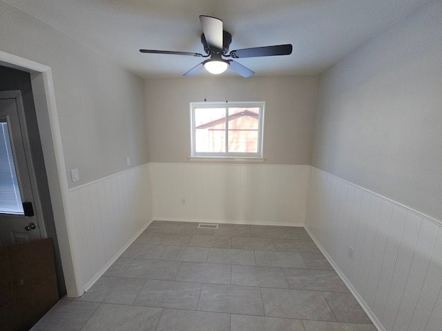 tiled empty room featuring ceiling fan