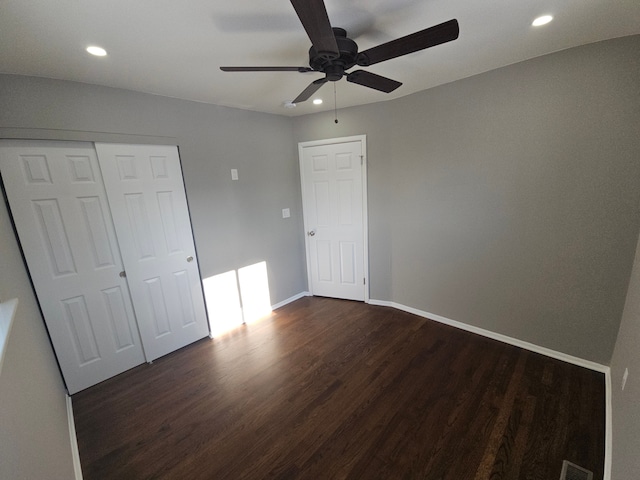 unfurnished bedroom with ceiling fan, a closet, and dark wood-type flooring