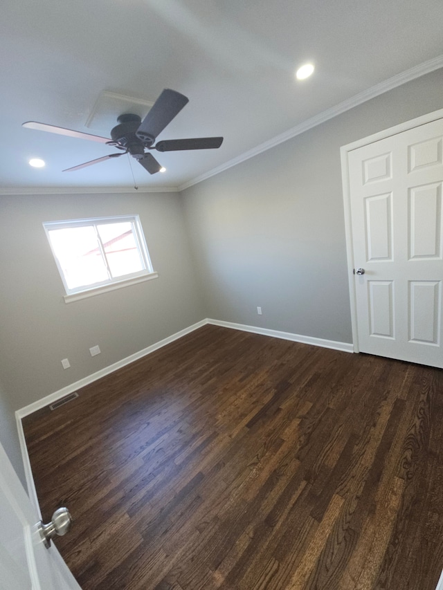 empty room with ceiling fan, dark wood-type flooring, and ornamental molding