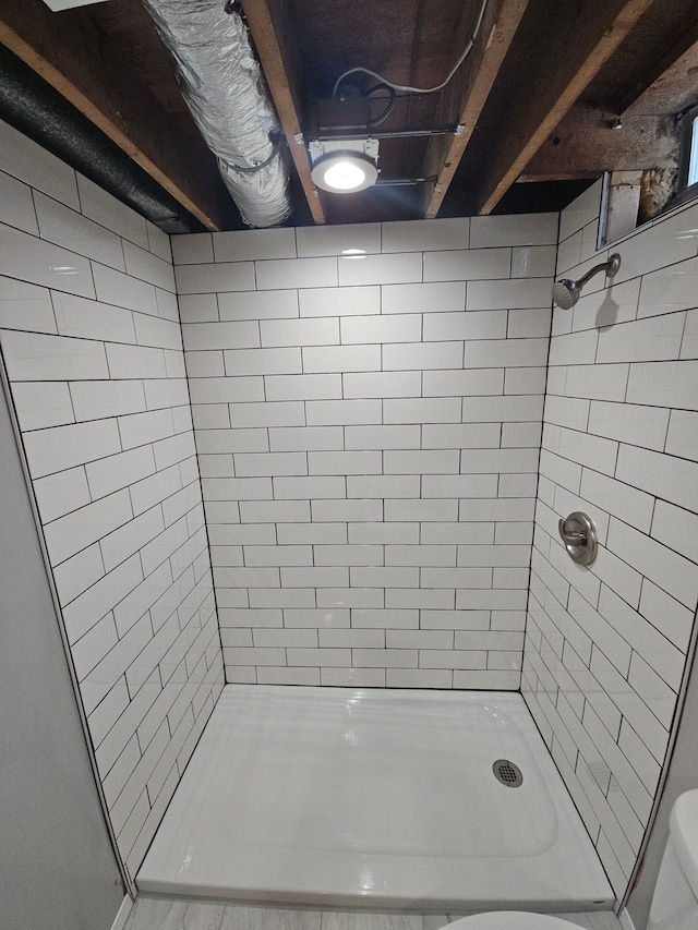 bathroom featuring a tile shower and toilet