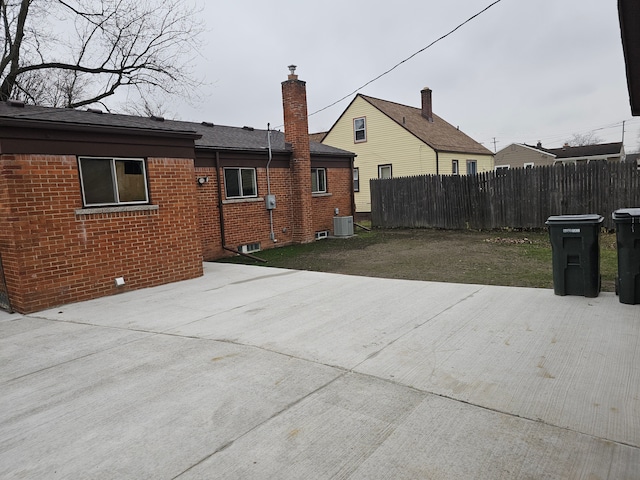 rear view of property featuring central AC unit, a patio area, and a lawn