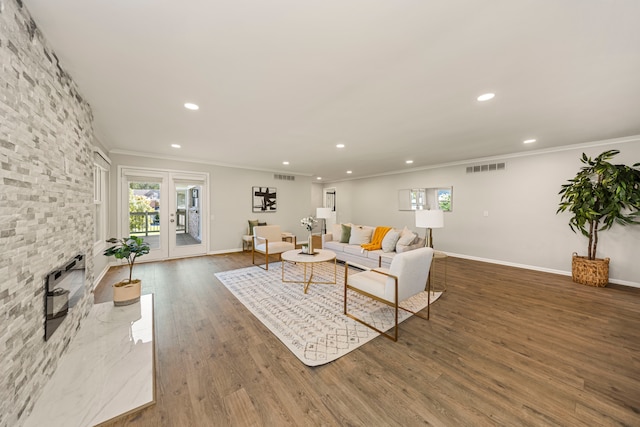 living room featuring a stone fireplace, dark hardwood / wood-style flooring, and crown molding