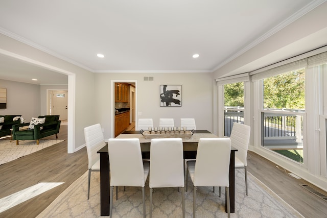 dining area featuring crown molding and light hardwood / wood-style flooring