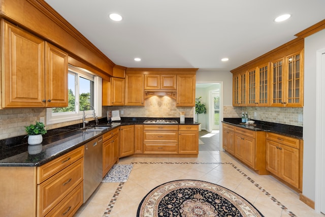 kitchen with backsplash, sink, dark stone countertops, ornamental molding, and stainless steel appliances