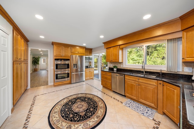 kitchen featuring sink, stainless steel appliances, tasteful backsplash, dark stone countertops, and light tile patterned flooring