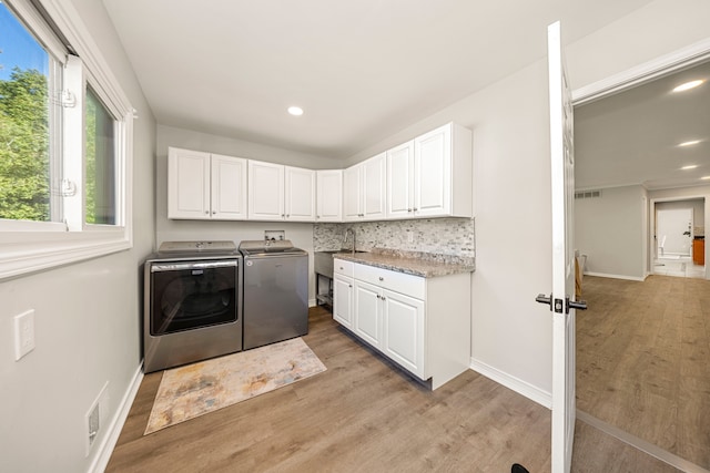 laundry room featuring cabinets, light hardwood / wood-style floors, washing machine and dryer, and sink