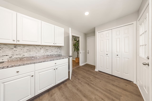 kitchen with decorative backsplash, white cabinetry, and hardwood / wood-style floors