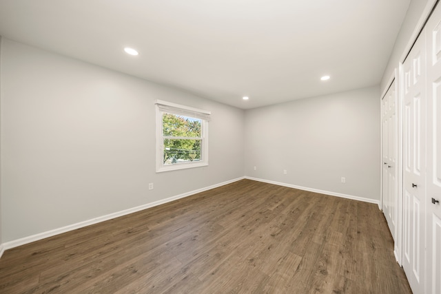 unfurnished bedroom featuring dark hardwood / wood-style flooring and two closets