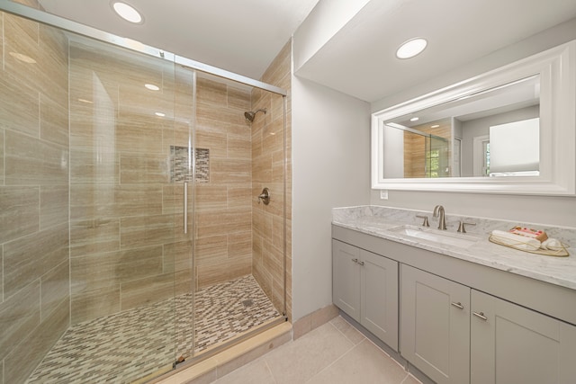 bathroom featuring tile patterned floors, a shower with door, and vanity