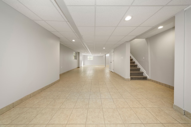 basement featuring a paneled ceiling and light tile patterned flooring