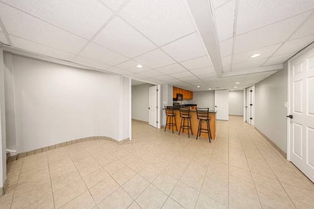 interior space featuring a breakfast bar and a drop ceiling