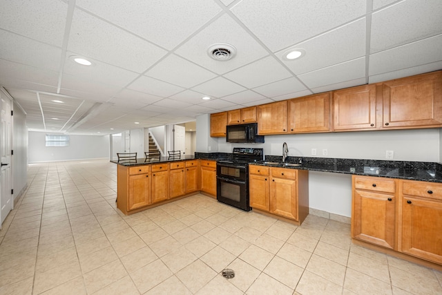 kitchen with kitchen peninsula, a drop ceiling, sink, black appliances, and dark stone countertops