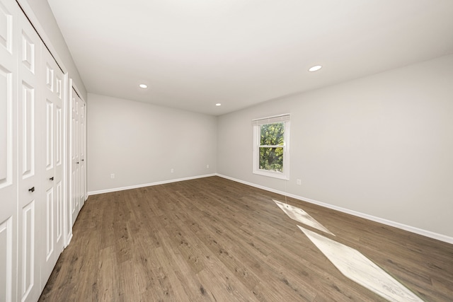 unfurnished bedroom with wood-type flooring and two closets