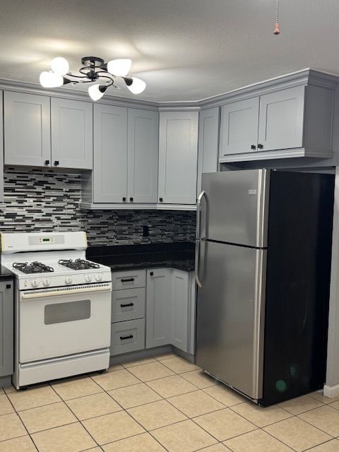 kitchen with white range with gas stovetop, stainless steel fridge, ceiling fan, and gray cabinetry