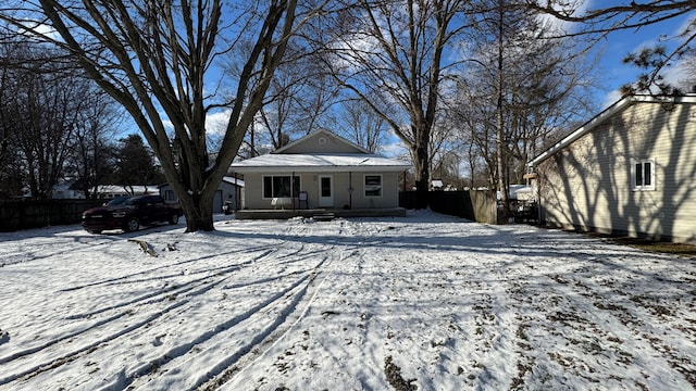 snow covered back of property featuring a porch