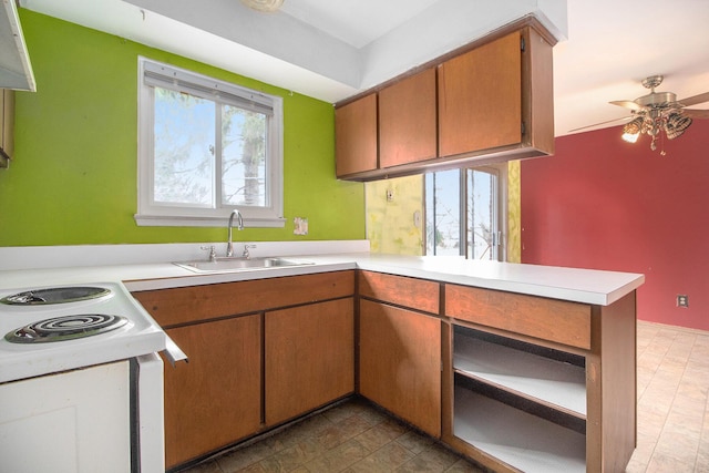 kitchen with ceiling fan, a healthy amount of sunlight, kitchen peninsula, and sink