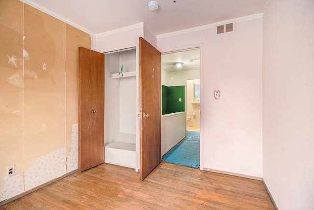 unfurnished bedroom featuring wood-type flooring, a closet, and crown molding