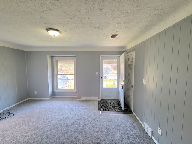 doorway to outside with a textured ceiling and carpet flooring