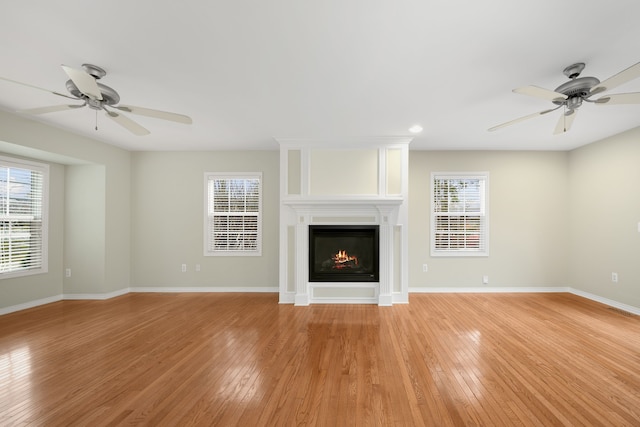 unfurnished living room with a large fireplace, a healthy amount of sunlight, and light hardwood / wood-style flooring