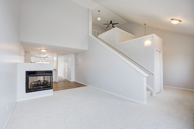 interior space with a multi sided fireplace, ceiling fan, carpet flooring, and high vaulted ceiling