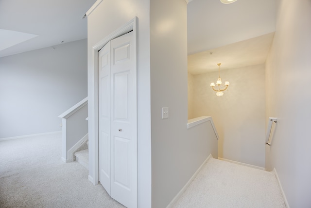 hallway featuring light colored carpet and an inviting chandelier