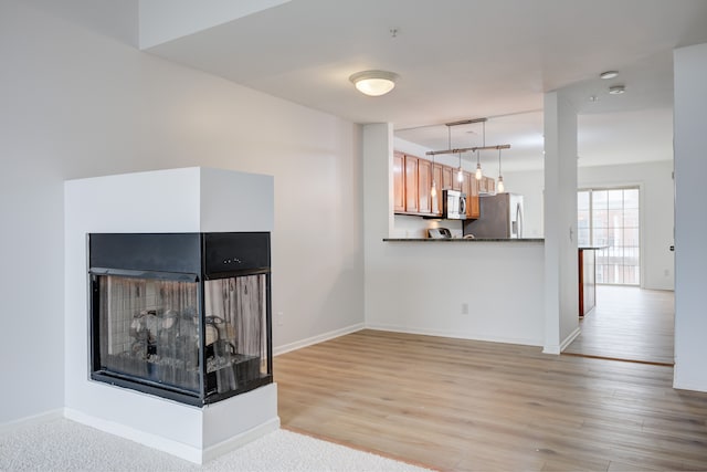 unfurnished living room with a multi sided fireplace and light wood-type flooring