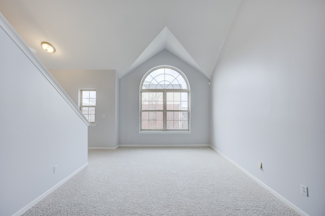 empty room featuring light colored carpet and vaulted ceiling