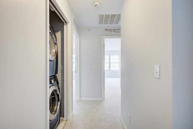 laundry area featuring stacked washer and dryer and light carpet