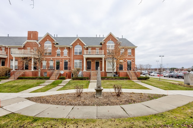 multi unit property featuring a balcony and a front lawn