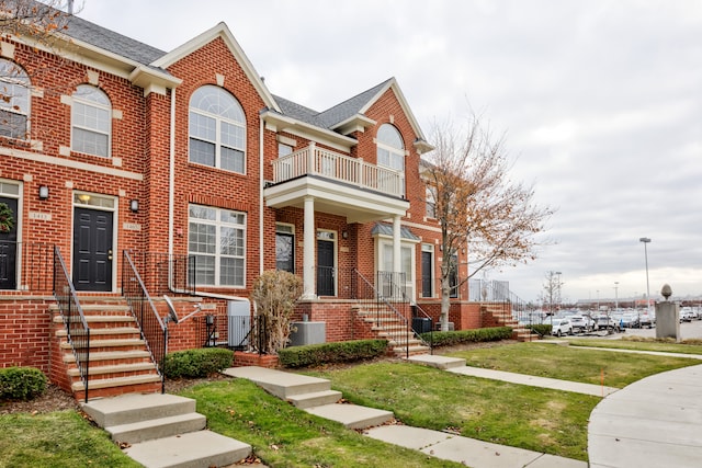 townhome / multi-family property featuring cooling unit, a balcony, and a front yard